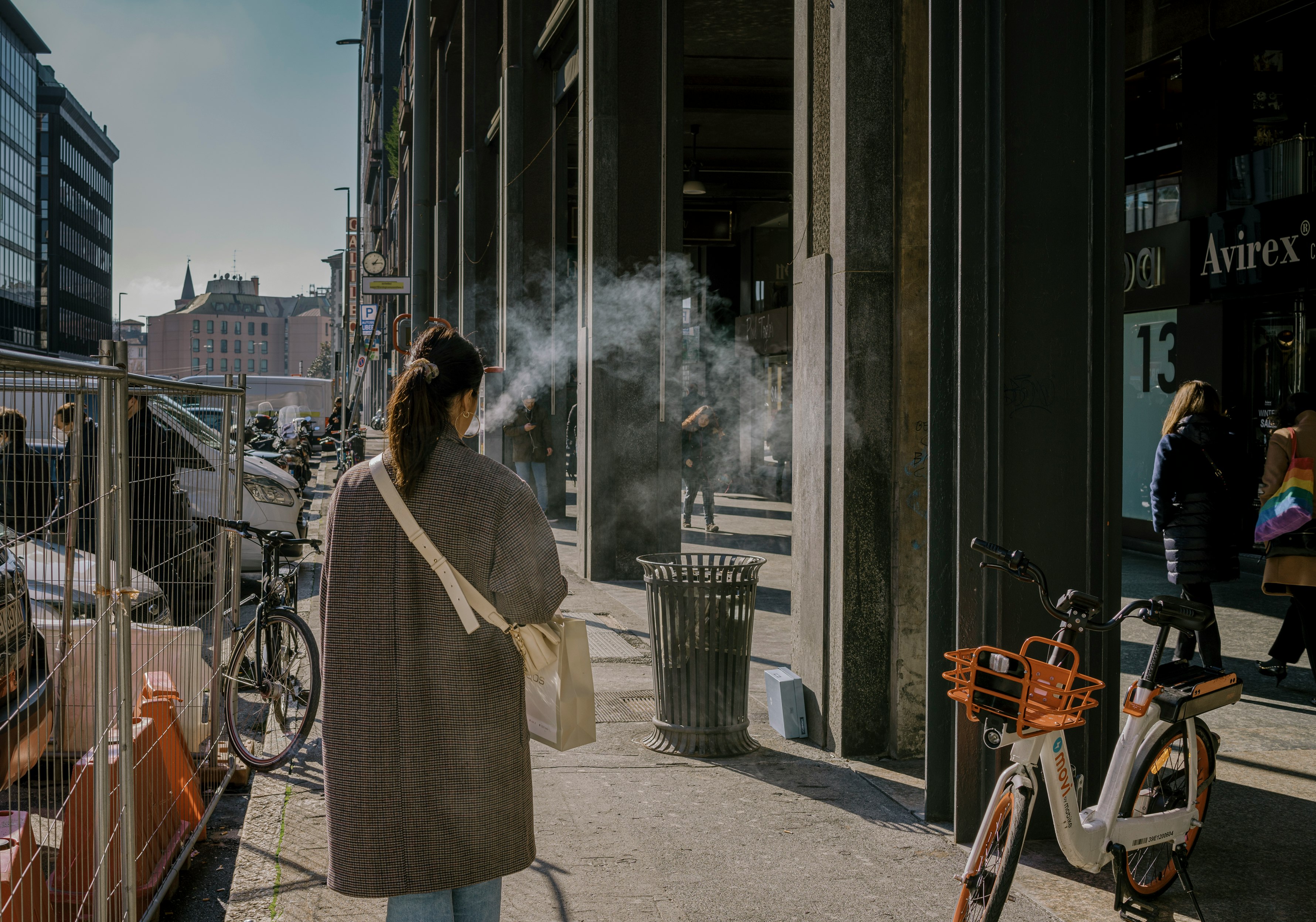 woman in white coat standing near brown wooden door during daytime